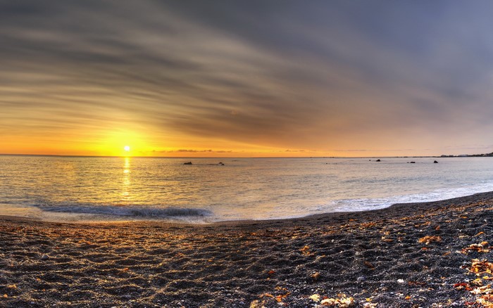 Sunset over a pebble beach and the ocean