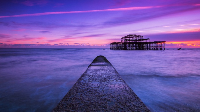 Ruined pier at sunset with purple and pink sky