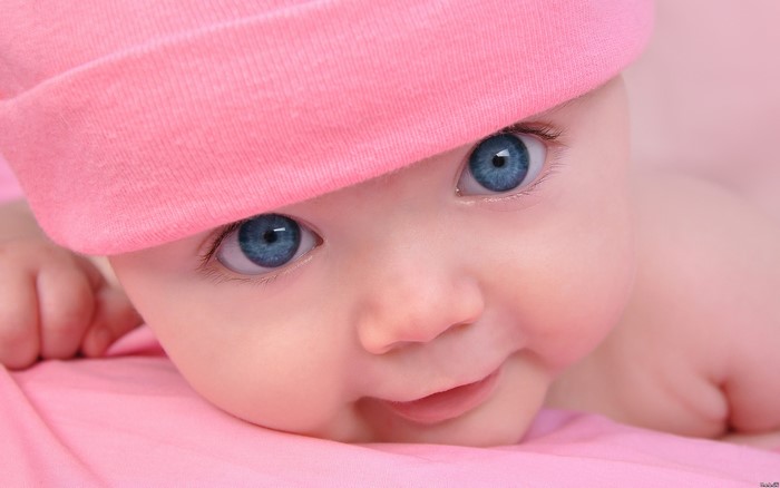 Baby with blue eyes wearing a pink hat