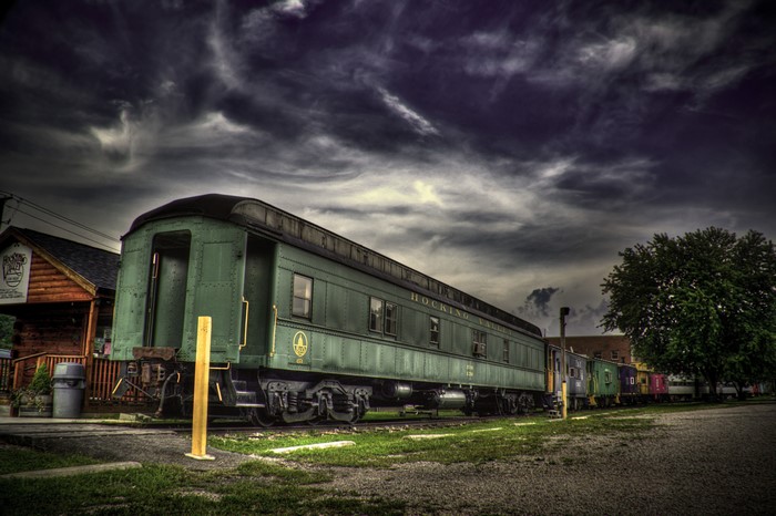 Green Hocking Valley train cars under a stormy sky