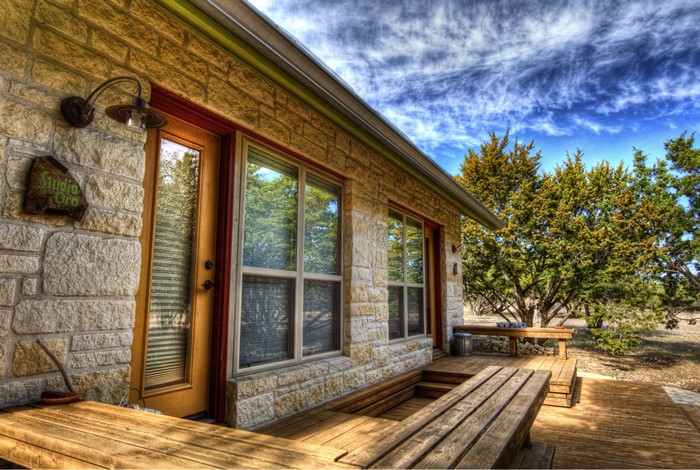 Stone house with wooden deck and trees