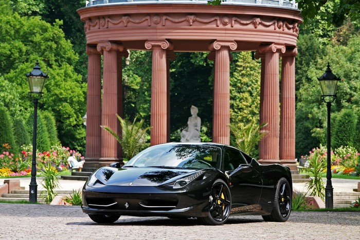 Black Ferrari parked in a garden with a gazebo