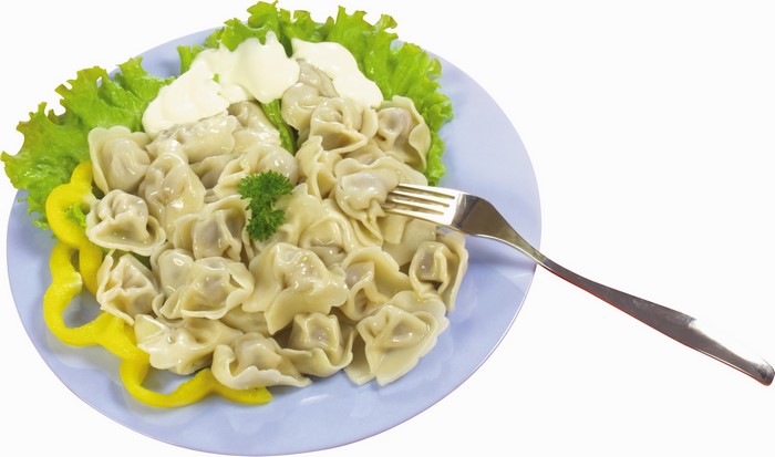 Plate of dumplings with sour cream and lettuce