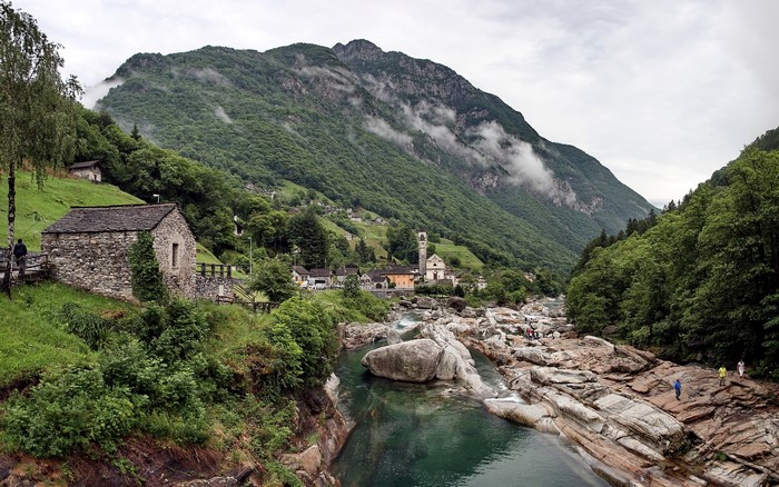 Stone house and church in a mountain valley with a river