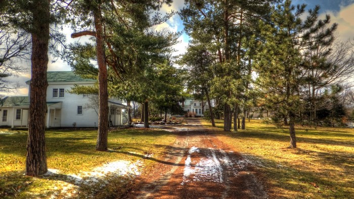White house with trees and dirt road in Michigan