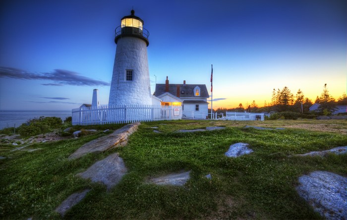 White lighthouse on a rocky coast at dusk