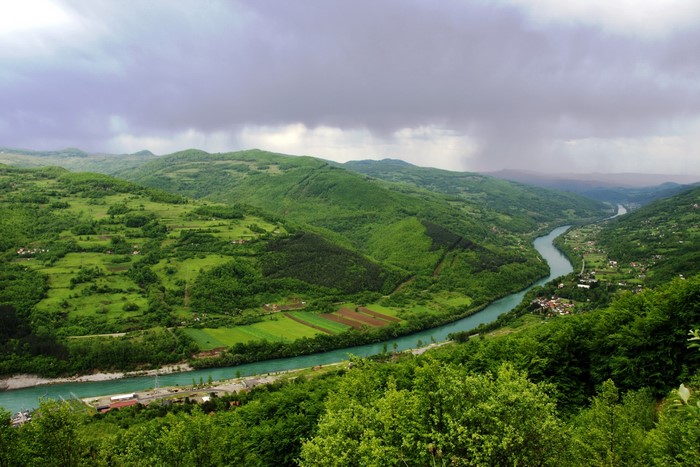 River valley with green hills and cloudy sky
