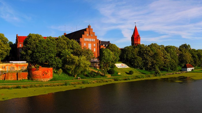 Brick building and red tower by the river in Poland