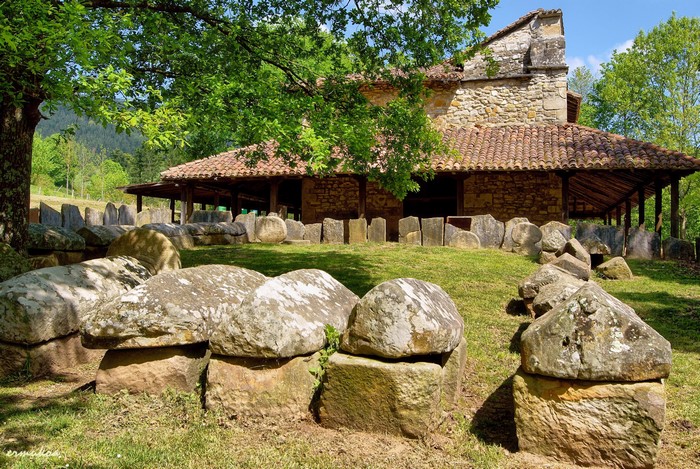 Ancient stone structures in front of a stone building in Spain