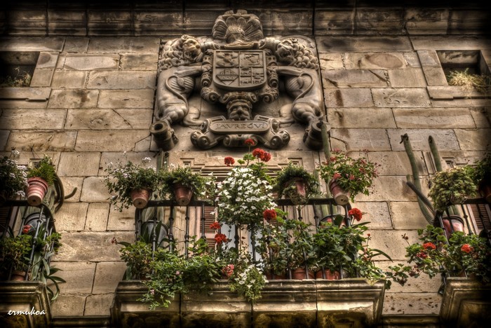 Coat of arms above balconies with flowers in Spain