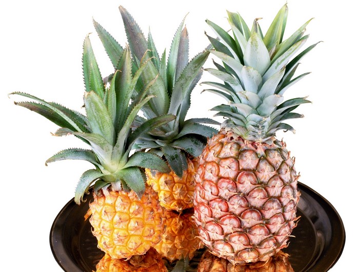 Three pineapples on a dark tray
