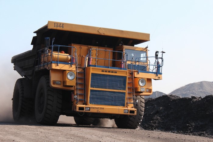 Yellow mining dump truck driving on a dirt road