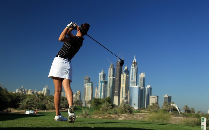 Woman playing golf in front of Dubai skyline