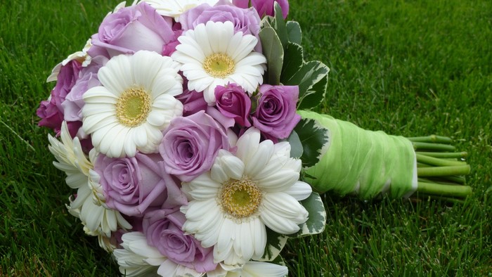 Purple roses and white daisies bouquet on grass