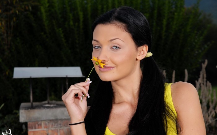 Aletta Ocean sniffing a yellow flower