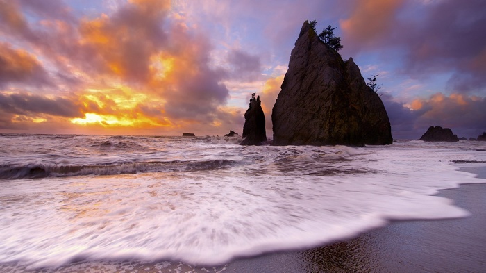 Sunset over rocky coast with crashing waves
