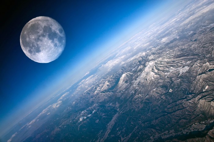 The Moon over Earth's mountains and clouds