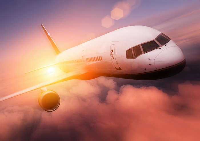 Airplane flying through clouds at sunset