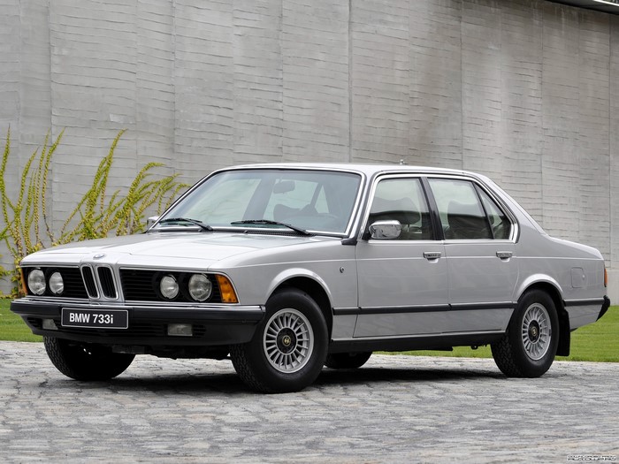 Silver BMW 733i parked in front of a textured wall