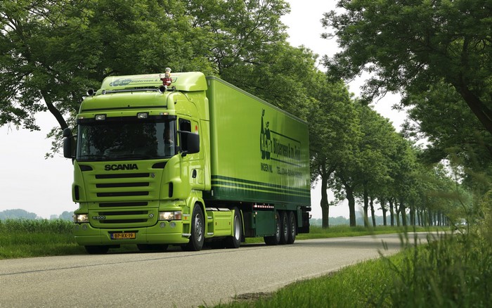 Green Scania Truck Driving on a Tree-Lined Road