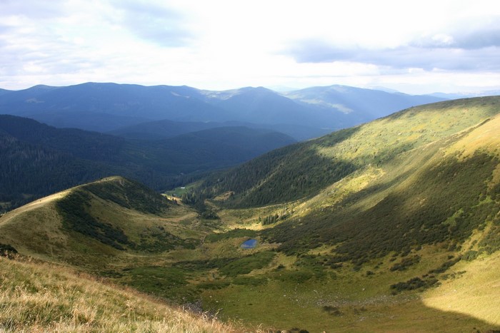 Mountain valley with a small lake and forested slopes