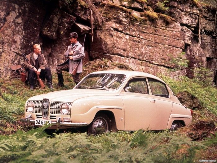 Two hunters and a vintage Saab car in a forest