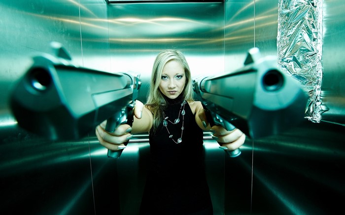 Woman holding two pistols in an elevator