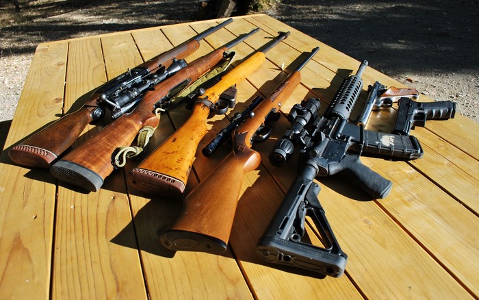 Rifles and handguns on a wooden table