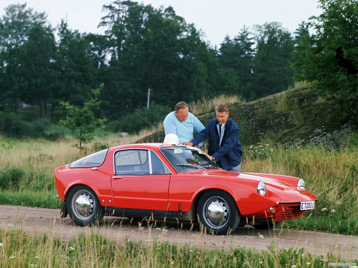 Two men looking at a red Saab Sonett car