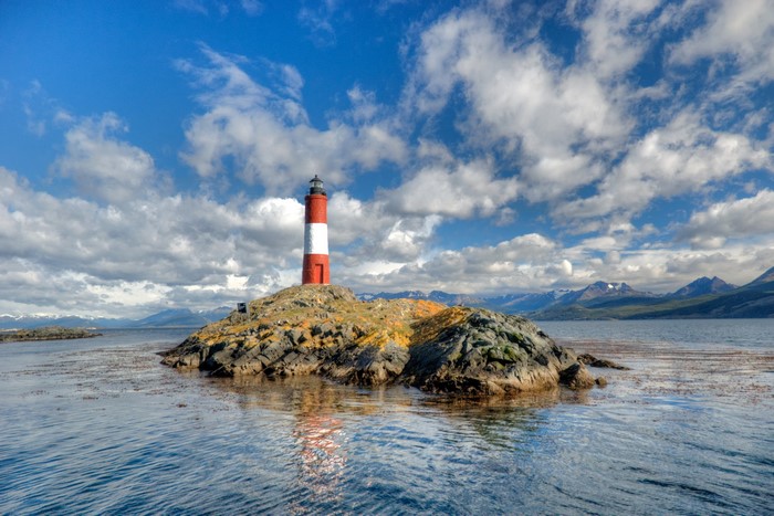Red and white lighthouse on a rocky island