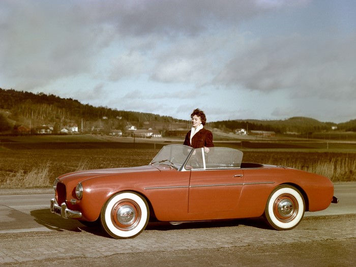 Woman with a red Volvo convertible in a rural landscape