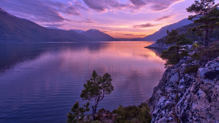 Purple sunset over a calm lake and mountains