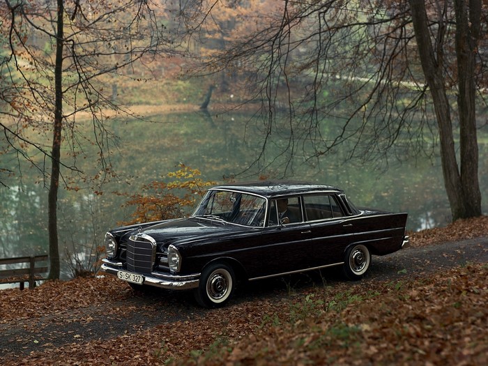 Black Mercedes-Benz W111 parked by a lake in autumn