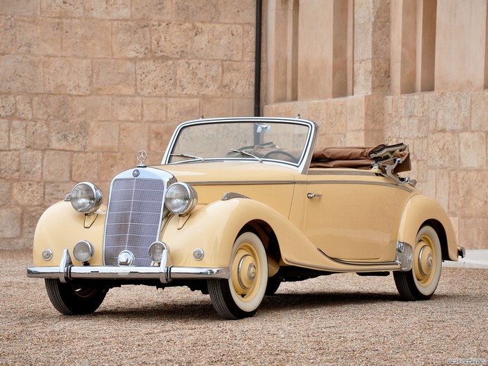 Yellow Mercedes-Benz convertible parked in front of a stone building