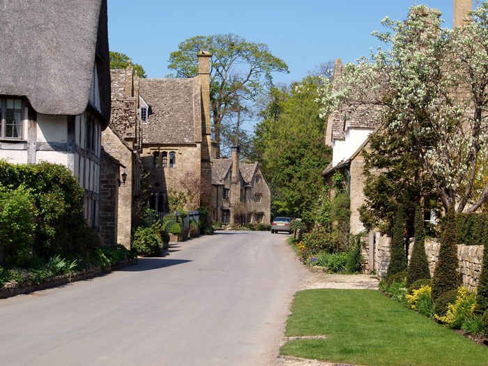 Cotswolds village street with stone houses and trees