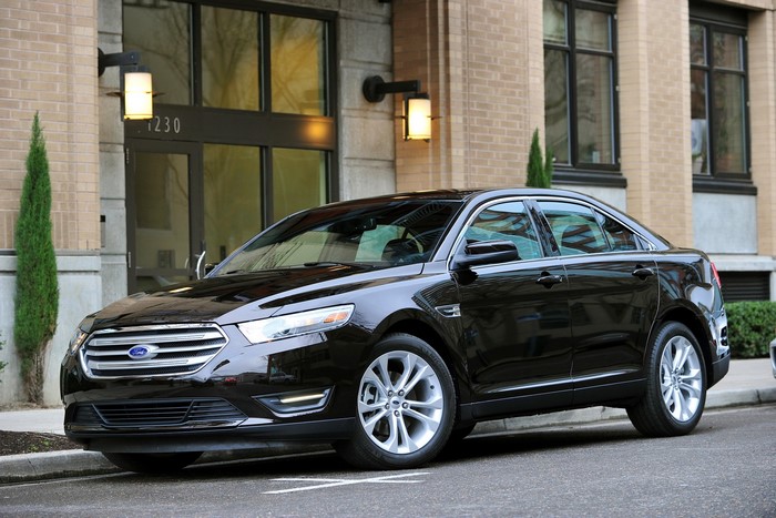Black Ford Taurus parked in front of a brick building