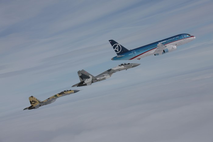 Sukhoi SuperJet-100 and fighter jets flying in formation