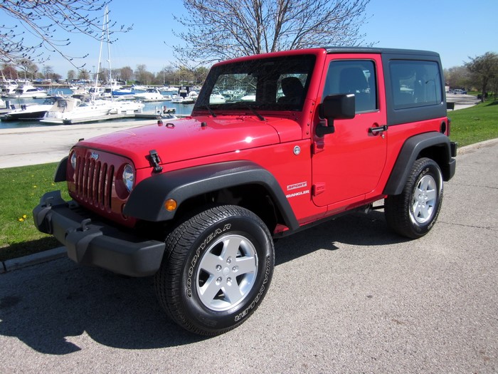 Red Jeep Wrangler Sport parked by a marina