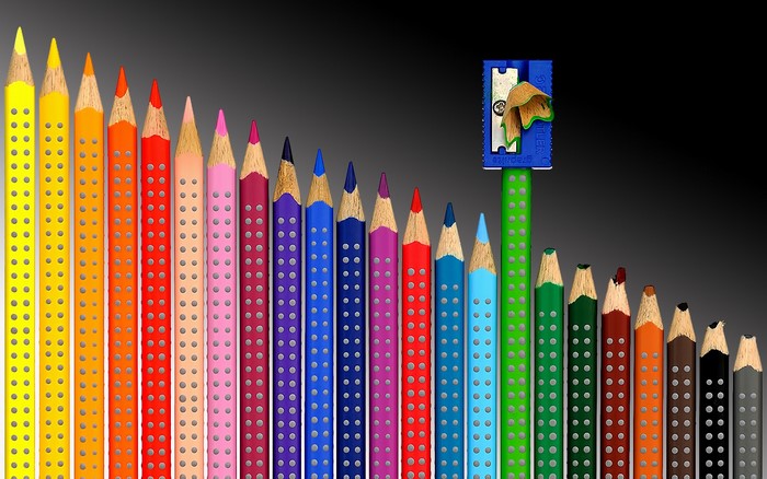 Colored pencils arranged in a descending line with a pencil sharpener