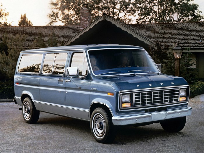 Blue Ford Econoline Van parked in front of a house