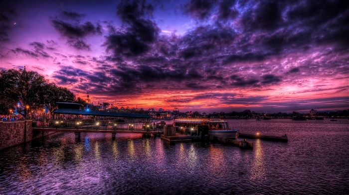 Boats docked on a lake during a vibrant purple and pink sunset