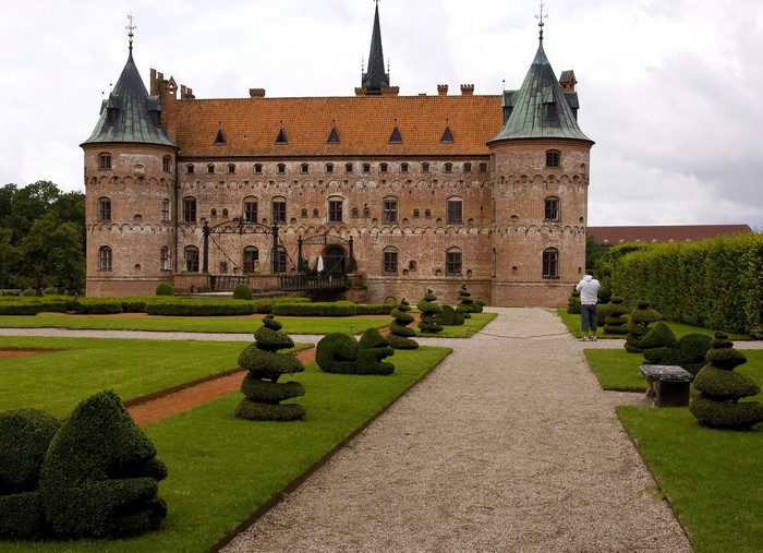 Castle with manicured gardens and a person taking a photo