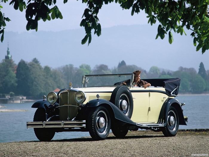 Woman in a vintage Maybach convertible by a lake