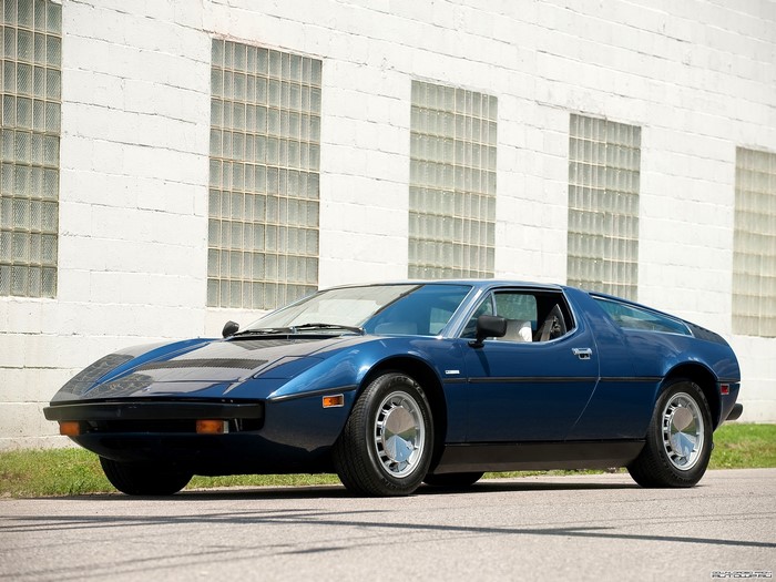Blue Maserati Bora parked in front of a white brick building