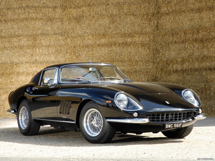Black Ferrari 275 GTB/4 parked in front of hay bales