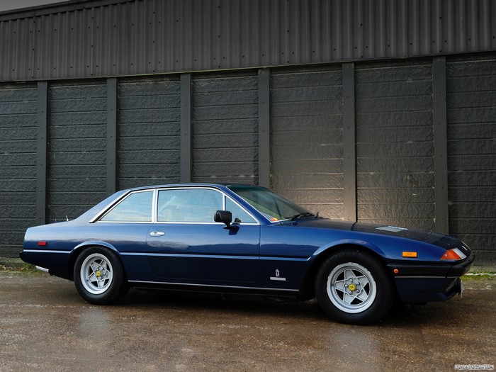 Blue Ferrari parked in front of a dark wall