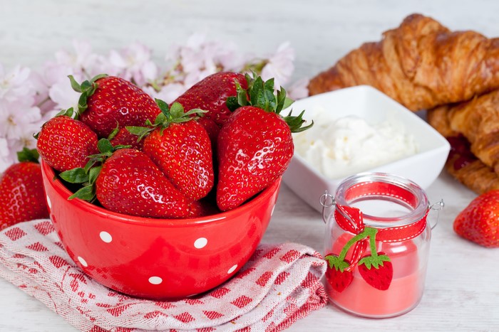 Strawberries in a bowl with croissants and cream