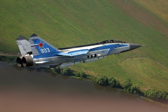 Russian MiG-31 fighter jet flying over a river