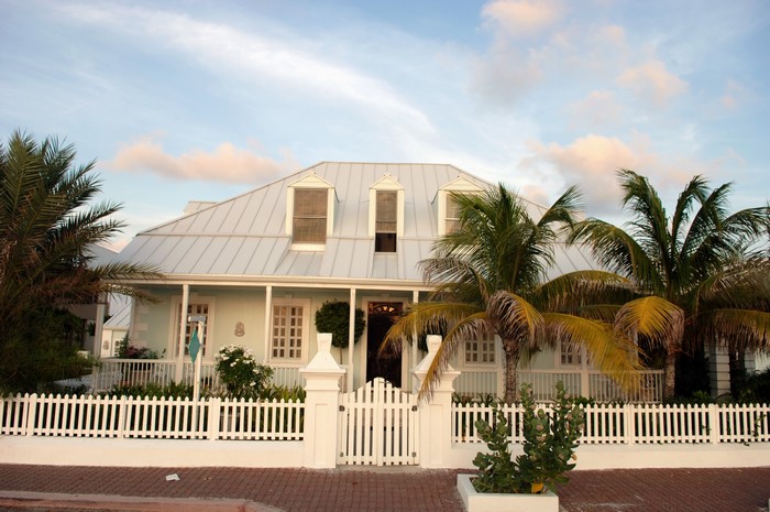Light blue house with white picket fence and palm trees