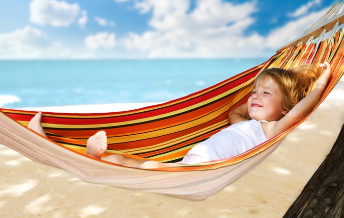 Little girl relaxing in a hammock on the beach